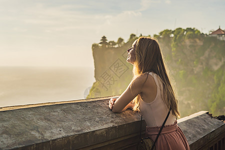 印度尼西亚巴厘寺庙的年轻女性旅行者 令人惊异的景观 — — 蓝天和大海悬崖背景