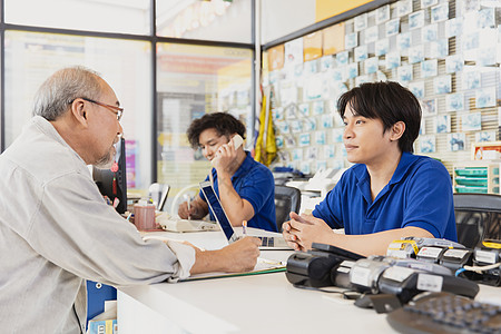 客户签署合同文件以申请会员资格 并在商店的柜台服务中与男性工作人员进行交谈和接见图片