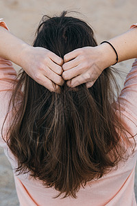 穿粉红色衬衫的女人用双手抓着她的自然毛发 长发的黑发女人 从后面看图片