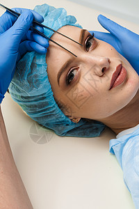 在整形外科手术前 在医疗诊所对面眼部区域进行整形改造时 将脸部上方的白光膜印记贴近塑料医院药品病人医生工作皮肤考试成人女性图片