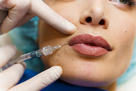 迷人女孩的丰唇注射 整形外科医生在诊所进行唇部注射 美容振兴面部护理身体治疗沙龙皮肤科临床胶原塑料药品程序手套图片