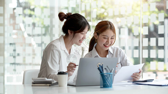 两位年轻的亚洲女商务人士讨论投资项目工作和规划战略 商界人士在办公室与笔记本电脑交谈伙伴企业家互联网网站顾问团队自雇电子商务女性图片