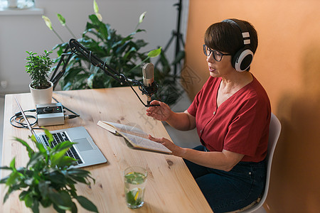 中年女电台主持人为在线节目制作播客录音  广播和 DJ 概念播送工作室笔记本耳机嗓音职业商业办公室打碟机音乐图片
