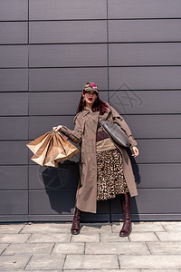 一个快乐的购物狂女孩把她的包放在购物中心附近 商店附近的一位女士拿着袋子对她购买的商品很满意 穿着豹纹连衣裙 消费观念黑色飞跃店图片