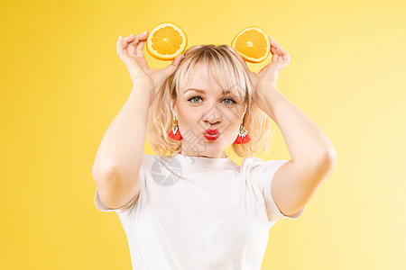 美丽的 快乐的女士玩橘子片 橙色圆圈 果汁广告 阴暗框 黄色背景化妆品果汁皮肤微笑成人橙子眼睛魅力食物饮食图片