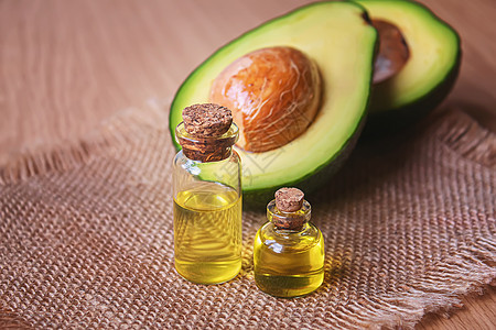 木本底的阿沃卡多和鳄梨油 有选择的重点健康疗法芳香玻璃化妆品水果治疗木头热带液体图片