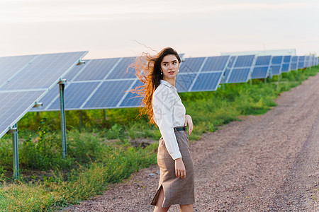 女孩站在日落时在地面的2个太阳能电池板之间 家庭免费用电 地球的可持续性 笑声电压活力环境工程蓝色生态资源技术植物控制板图片