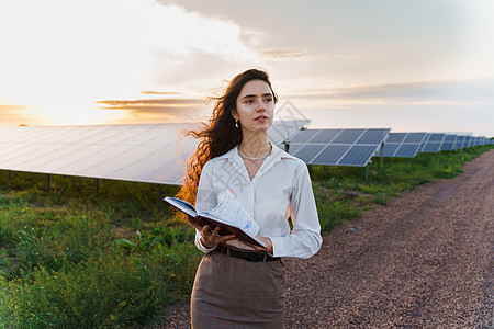 日落时 投资者妇女站在太阳能电池板行附近看书 地球的可持续性 笑声太阳能阳光太阳蓝色工程植物资源活力技术发电厂图片