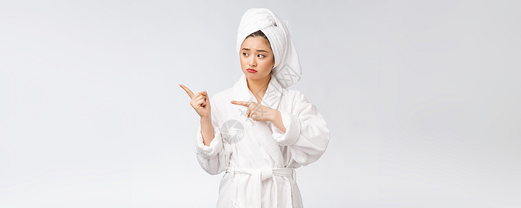 年轻美女洗完澡后穿着浴巾 在孤立的白色背景下用手指指着她沉思皮肤手势成人女士化妆品相机女孩女性情绪图片