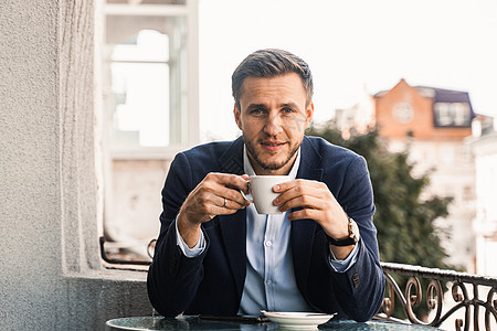男人喜欢咖啡 英俊的男人在咖啡馆里喝杯咖啡 男性的早晨生活方式 男人坐在咖啡馆的夏日露台上 边喝咖啡边微笑办公室软垫人士电脑桌子图片