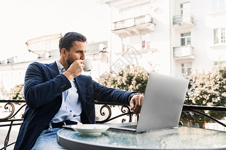 有咖啡杯的帅哥正在网上工作 在咖啡馆使用笔记本电脑 远程工作互联网软垫桌子咖啡商务杯子短信办公室男人屏幕图片