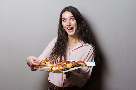 女孩信使与灰色背景的意大利美食 拿着传统菜 比萨店送餐 Pinsa 配肉 芝麻菜 橄榄 奶酪食物桌子火腿午餐导游送货小吃杂烩香肠图片