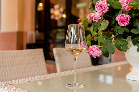 在光桌白花瓶的花朵背景上 杯白葡萄酒 彩虹玫瑰桌子白色花束绿色酒精咖啡店粉色服务反射庆典图片