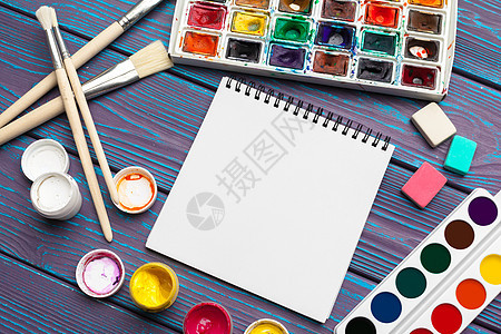 绘画工具 固定用品 艺术家工作场所 水彩油漆和木制桌上的空白笔记纸图片
