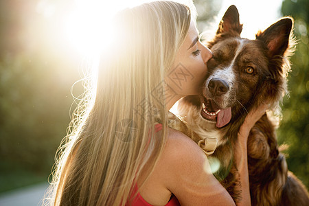 在公园里亲狗的年轻女子近距离肖像拥抱日光朋友闲暇犬类女孩喜悦女性宠物微笑图片