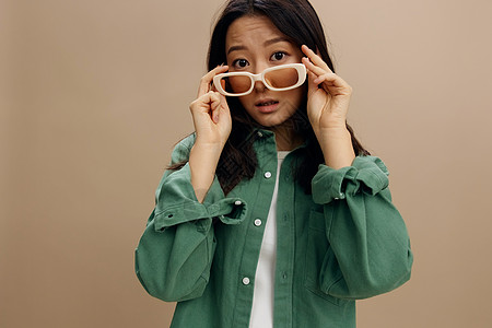 穿着卡其青绿衬衫 时装眼罩张开口的韩国年轻女士震惊地兴奋不已 说出秘密八卦 在米色糊面工作室背景上与世隔绝图片