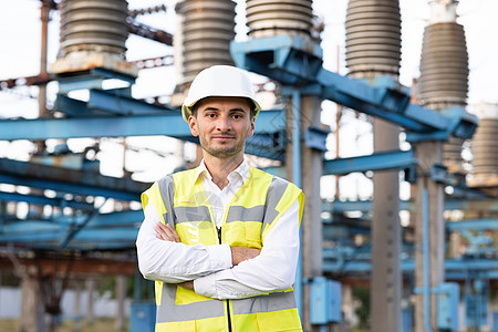 年轻微笑的亚洲电力工人双臂交叉在电力现场的画像 站在高压电站的安全帽工程师工人肖像图片