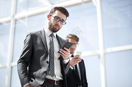 两个有智能手机的商务人士电话男人大堂工作细胞同事经理玻璃商业套装图片