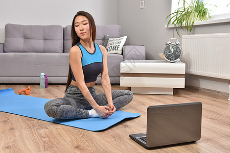从事在线培训瑜伽的年轻女性教程互联网电脑训练姿势女孩地面运动装笔记本房间背景图片