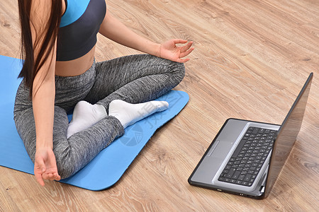从事在线培训瑜伽的年轻女性教程姿势互联网爱好训练身体运动装笔记本女孩运动背景图片