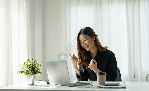 欢欣鼓舞的年轻商业女青年女性以举臂庆祝成功的形象 在商业概念中表现积极 发扬光大经济庆典预算女士投资生长工作快乐利润货币图片