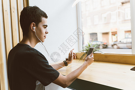 青年成人在智能手机上发短信 在咖啡馆听耳机上的音乐;生活方式 业余时间 休息 放松图片