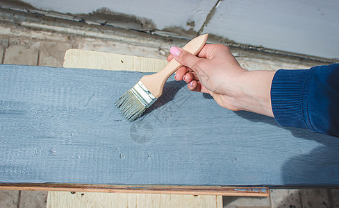 女孩用刷子画板 用灰色涂漆松树建造木头绘画装潢地面工作画家露台桌子图片