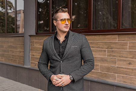 时尚的年轻小伙子肖像 在露天街上穿着灰色夹克和墨镜黑衬衫的欧洲外观商务人士成人套装男人太阳镜潮人城市衣服眼镜商务外套图片
