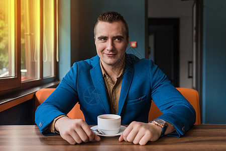 一张穿着蓝色夹克和棕色衬衫的白种人成年商务人士肖像坐在咖啡馆的桌子旁 休息时喝着咖啡图片