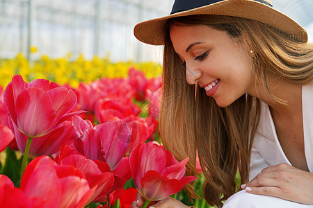 快乐的美丽女孩 有稻草帽 闻着盛开的郁金香味 在准备收获的农场上图片