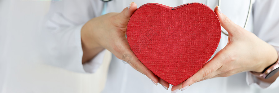 医生把红玩具心脏放在诊所闭诊室图片
