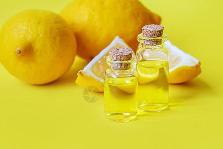黄色背景的柠檬基本油 有选择性的焦点温泉植物香水香气按摩身体治疗玻璃化妆品药品图片