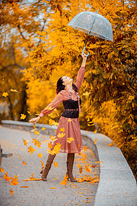 秋天公园穿着带雨伞的漂亮女孩 她把他抱在头顶上 秋叶从他身上掉出来森林树叶街道季节头发乐趣下雨女士公园衣服图片