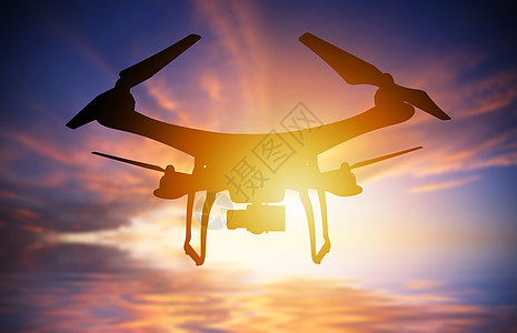 以数码相机在日落天空中飞行的无人驾驶飞机的休光灯图片