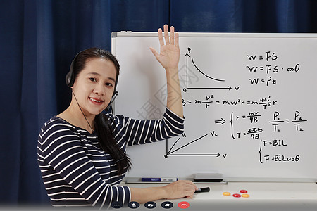 在家工作的亚洲学校女教师向在家学习的学生教授在线数学 covid19 大流行期间教师在白板上书写并在耳机互联网教育课上讲话课堂隔图片
