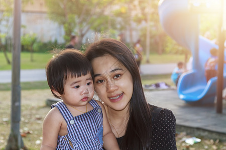 幸福的亚洲母亲和女儿的画像 操场公园里的亚洲女人和蹒跚学步的小女孩 幸福的家庭在游乐场公园一起玩耍孩子们女孩拥抱太阳妈妈童年婴儿图片