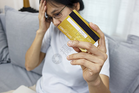 女性的近手握着信用卡 感到压力很大 不开心 担心网上购物过度购物问题带来的收税债务负担图片