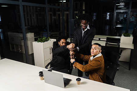 与笔记本电脑连线的多种族团队合作 非洲和亚洲同事手握拳头 社区精神和友谊 保持高度的积极性 掌声世界团结青年一体性联盟动机朋友们图片
