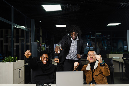 情感和快乐的非洲黑人和亚洲人团队合作 并在在线项目结束时欢欣鼓舞 多民族同事在笔记本电脑上工作 举起手 握紧拳头 大声喊叫伙伴会图片