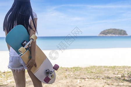 年轻女性拿着海滩背景的冲浪滑板 女性站在冲浪滑板上放松 享受带复制空间的热带海滩木板活动速度阳光极限平衡滑冰公园爱好闲暇图片