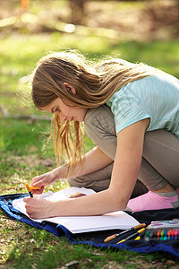 年轻少女在笔记本或日记上写作或在草地上的毛毯上画颜色染色微笑享受幸福创造力青少年金发女郎女孩学习阳光图片