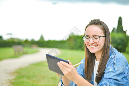 年轻美丽的女学生女孩在户外学习校园公园女性长椅图书大学幸福微笑背包教育图片