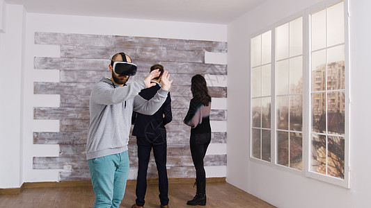 白种男人在空公寓里使用虚拟现实的头头团队装修模拟器财产女士女朋友中介房主经纪人眼镜图片