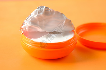 橙色背面橙色容器中的奶油霜图片