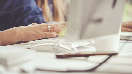 女商务人士在办公桌上用电脑打字咖啡办公室老鼠客户手指套装蓝色监视器顾客手术图片
