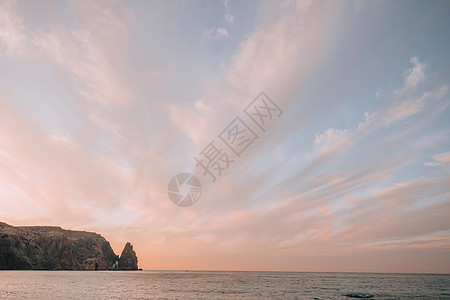 海上的红色燃烧日落与岩石火山悬崖 抽象自然夏季或春季海洋背景 金色温暖水面上的小波浪与来自太阳的散景灯天空温泉旅行火花海滩假期运图片