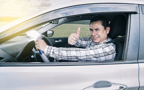 一个男人在开车时竖起大拇指的肖像 一个男人在他的车里竖起大拇指 一个快乐的男人在他的车里竖起大拇指图片