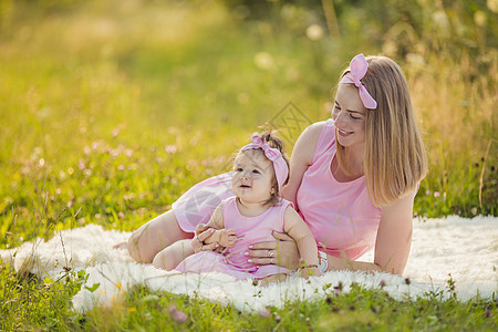 母亲和女儿穿着粉红裙子妈妈女性孩子微笑场地快乐女孩金光生活化妆品图片