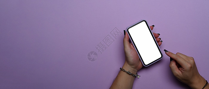 女性手使用手机 在紫色背景上隔开空屏幕 最顶端视图图片