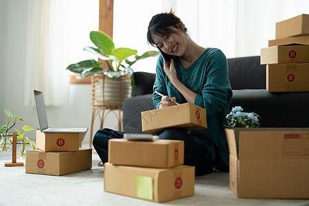 企业主在工作场所的纸板箱上写地址 自由职业女卖家准备产品包裹盒以交付给客户 在线销售 电子商务 运输概念船运商务零售营销物流自由图片